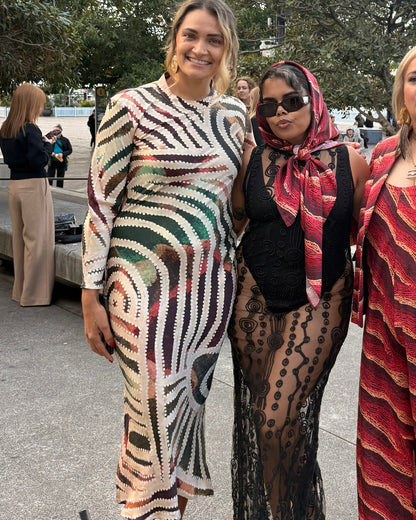 Two Aboriginal women posing outdoors, All wearing Aboriginal artwork clothing