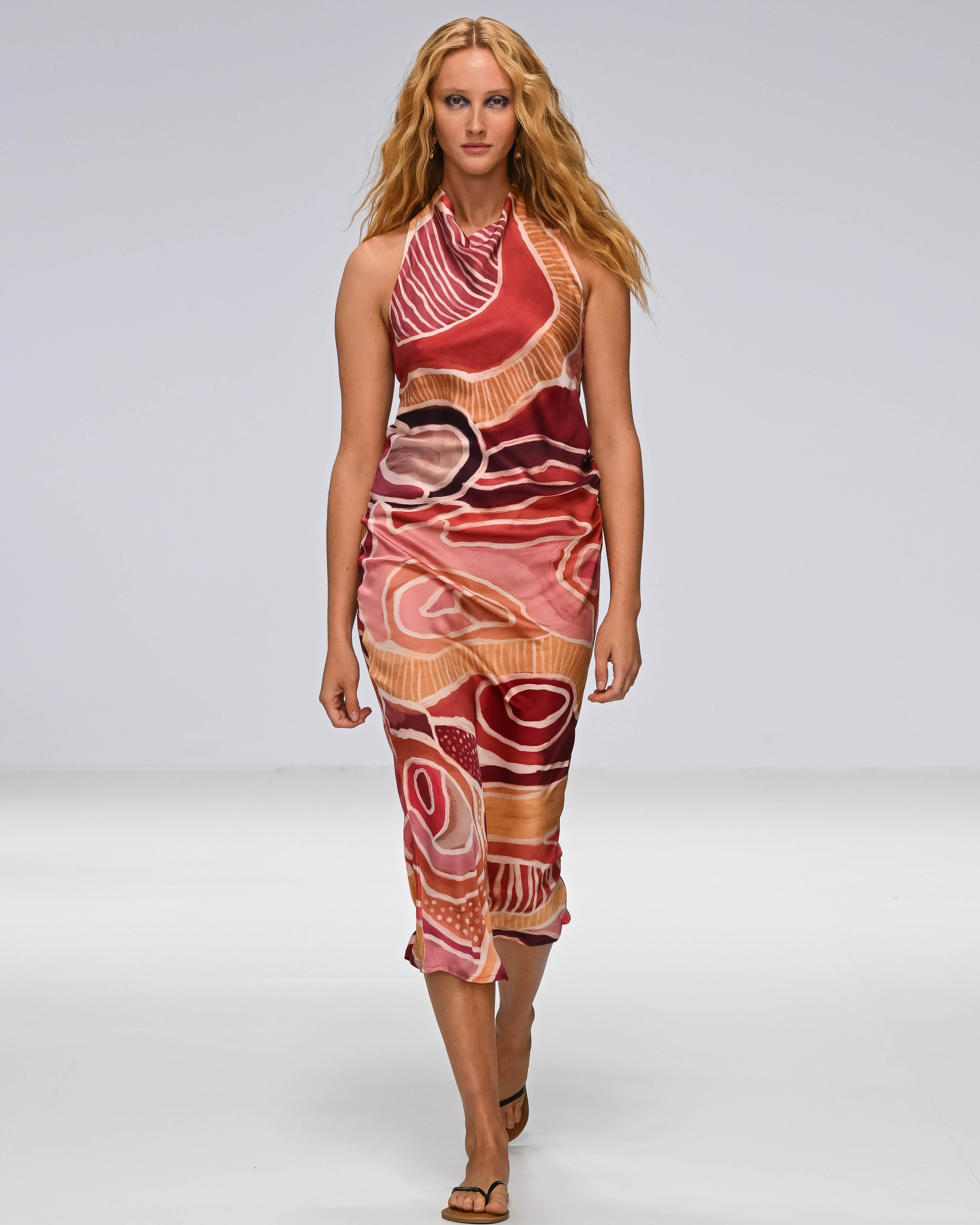 A Woman in a First Nations designed dress walking down a catwalk