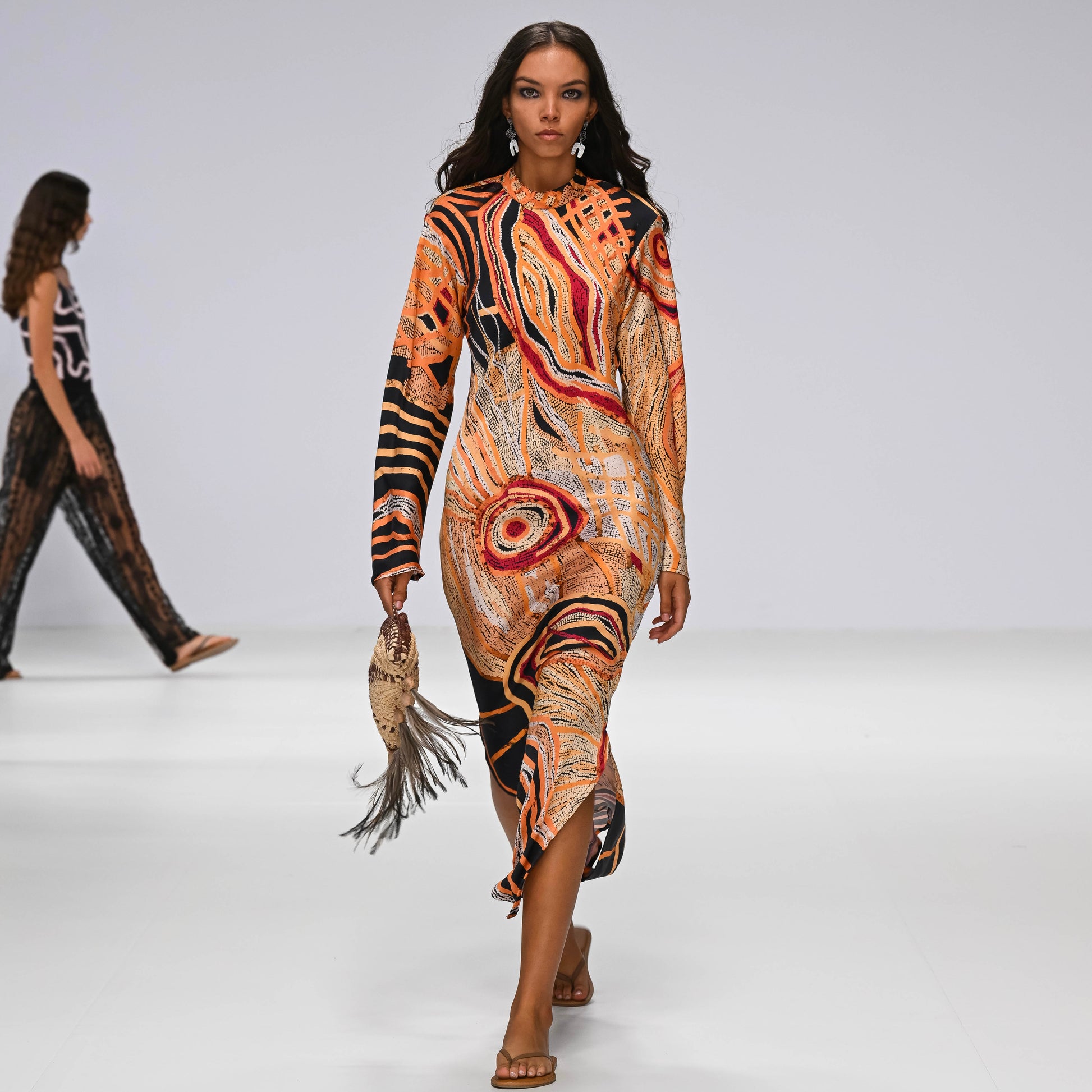 Model walking on a runway wearing a Aboriginal artwork dress.