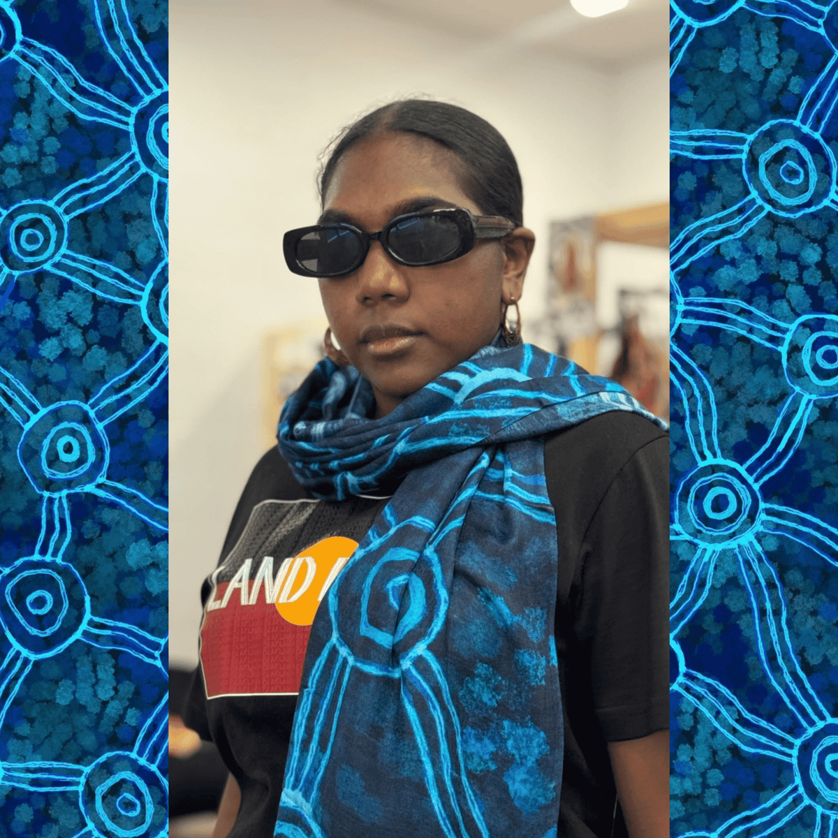 A Aboriginal woman wearing a brightly coloured blue scarf with Aboriginal artwork in the KINGKING shop