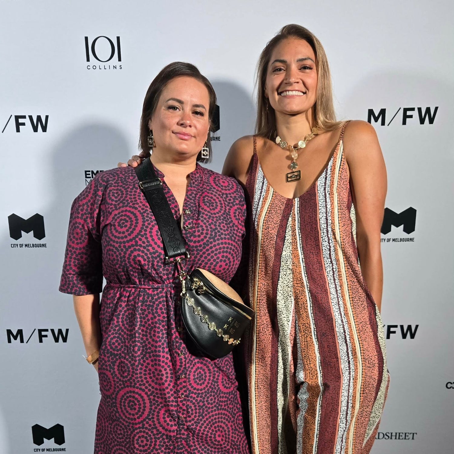 Two women posing together at a fashion event with 'MFW' branding in the background.